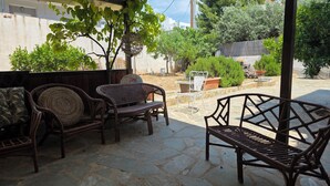 A patio with wicker furniture, stone flooring, and potted plants. - Charming Glyfada Family Appartment close to the Beach & City center | Quiet Area (Glifada)