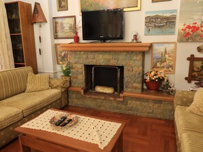 A living room with a fireplace, a television, and various decorative items. - Charming Glyfada Family Appartment close to the Beach & City center | Quiet Area (Glifada)