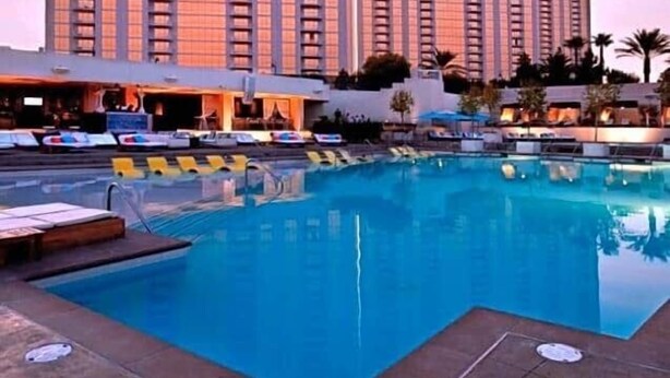 Um hotel com uma piscina grande, edifícios altos e céu claro.