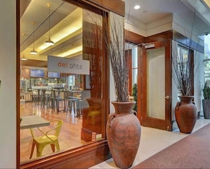 A modern interior with a restaurant named 'delights' visible through a glass door, large vases, and a wooden floor. - Penthouse Balcony Suite in Tower 3 (Las Vegas)