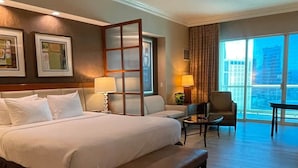 Quarto de hotel com uma cama grande, uma escrivaninha, uma cadeira e vista para a cidade.