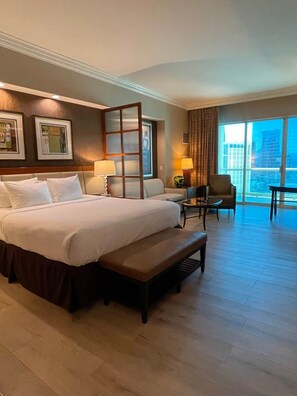 A hotel room with a large bed, a desk, a chair, and a view of the city. - Penthouse Balcony Suite in Tower 3 (Las Vegas)