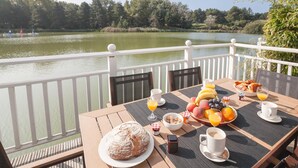 Een tafel met ontbijtartikelen, een brood en uitzicht op een meer.