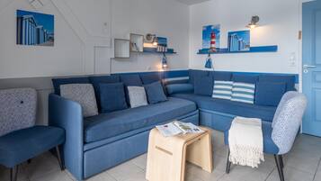 A modern living room with a blue sofa set, a wooden side table, and a patterned armchair.