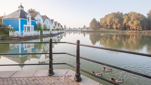 Een rustige rivier met een rij traditionele huizen, een brug en een houten omheining.