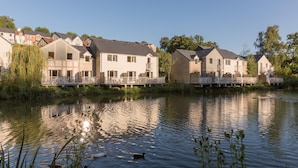 Un quartier résidentiel bordé de maisons le long d’une rivière, avec des balcons et une terrasse en bois.