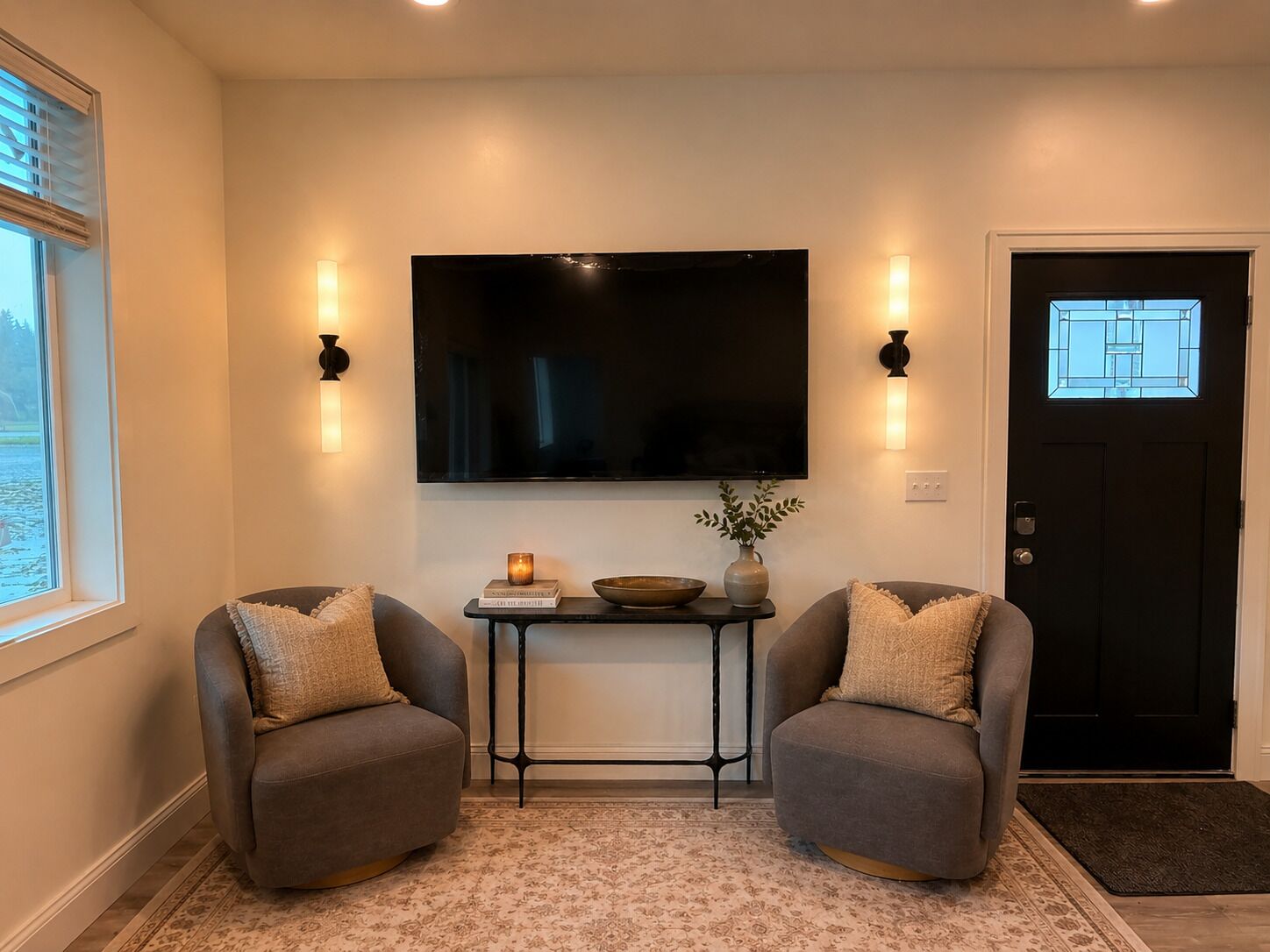 A living room with two armchairs, a coffee table, a flat-screen TV, and a door with a window.