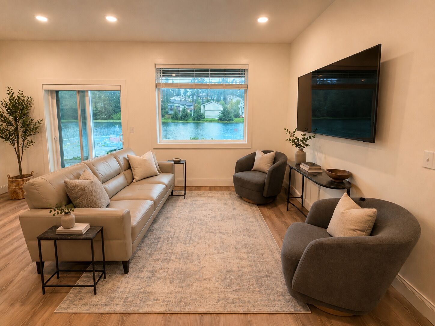 A living room with a sofa, armchairs, a TV, a window with a view, and a small table with a plant.
