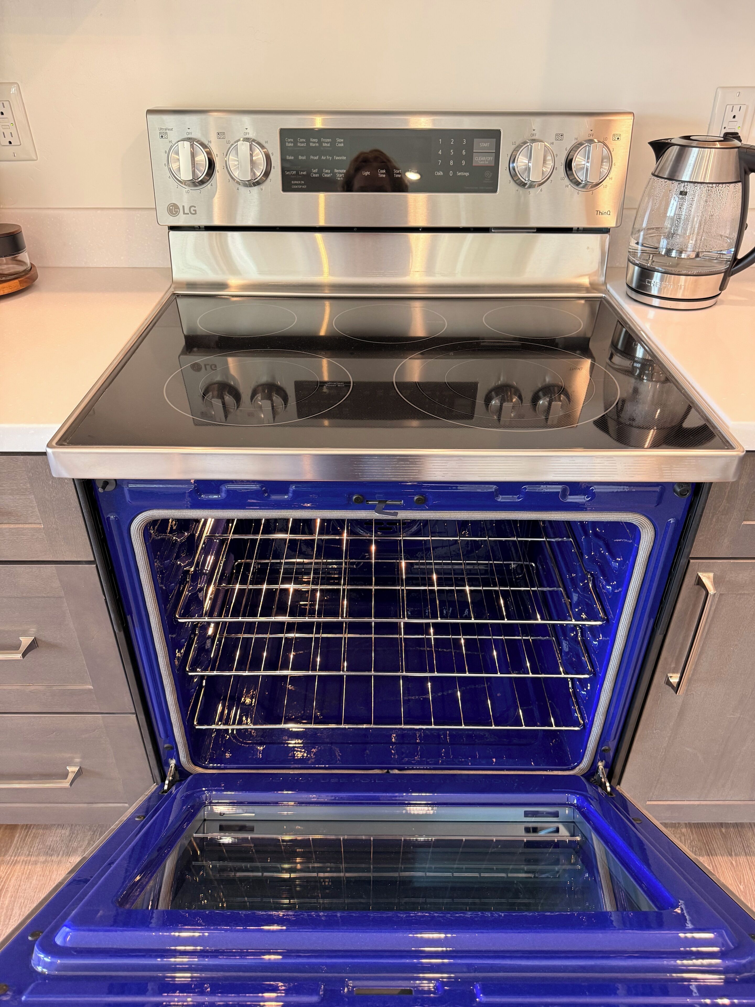An open stainless steel oven with a digital control panel and a glass door.