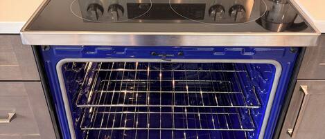 An open stainless steel oven with a digital control panel and a glass door.