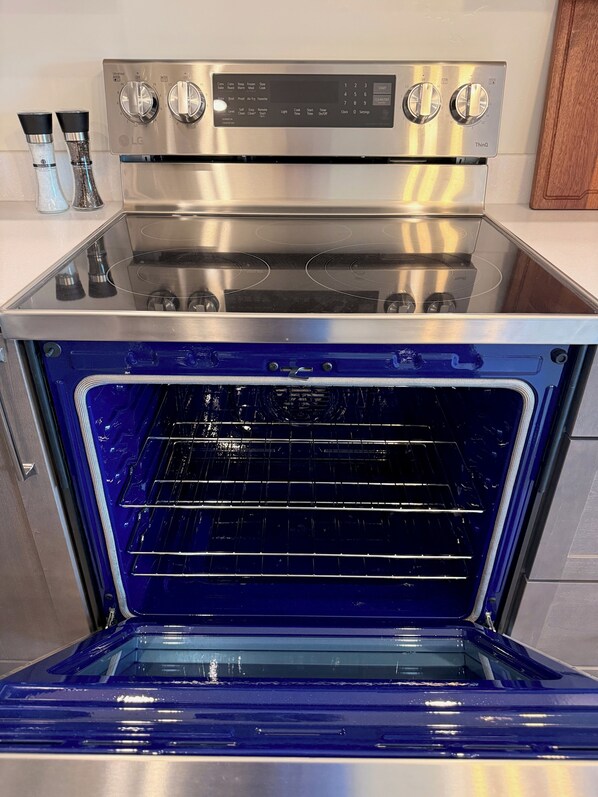 A stainless steel oven with a digital control panel and a blue interior. - Kodiak Suites (Kodiak)