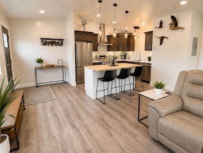 Una cocina moderna con una isla central, taburetes de bar e iluminación colgante.