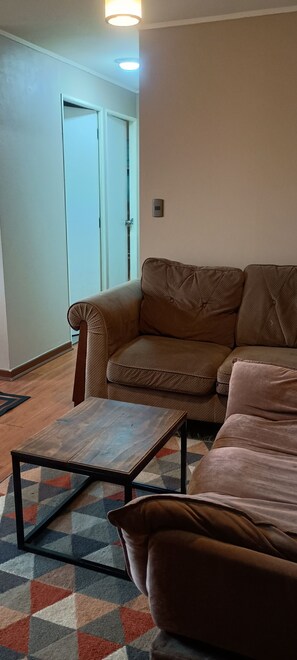 Un salon avec un canapé marron, une table basse en bois et un tapis à motifs.