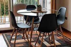 A modern dining area with a glass table, black chairs, and a patterned rug. - Comfortable Apartment for 4, Near Downtown (Temuco)