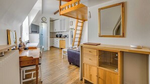 A loft-style room with a wooden loft bed, a dining table with chairs, a kitchen area, and a large mirror. - Studio 2P Near Tolbiac / Olympiades (Paris)