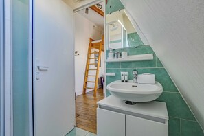 A bathroom with a white sink, green tiles, a mirror, and a wooden ladder. - Studio 2P Near Tolbiac / Olympiades (Paris)