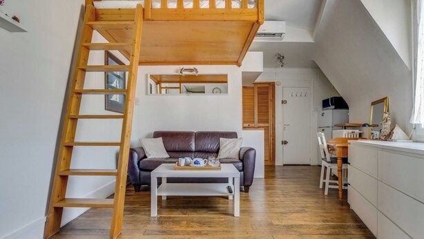 A loft-style room with a wooden ladder, a sofa, a coffee table, and a dining area. - Studio 2P Near Tolbiac / Olympiades (Paris)