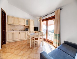A compact living space with a kitchenette, a dining area, and a sofa. - Chic Sardinian Escape by the Beach (Badesi)