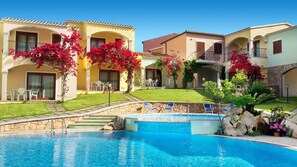 A hotel with a swimming pool, outdoor seating, and lush landscaping. - Chic Sardinian Escape by the Beach (Badesi)