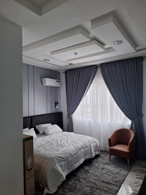 Ein modernes Hotelzimmer mit einem großen Bett, einem Sessel und einer Decke mit Einbauleuchten.