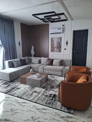 Una sala de estar moderna con un sofá modular, una mesa de centro y dos sillones.