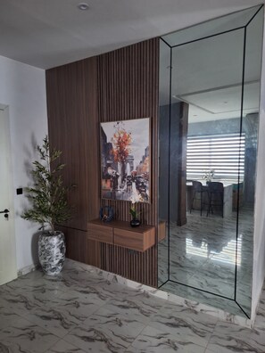 Ein modernes Interieur mit einer Holzwand, einem Stadtbild in einem Rahmen, einem Marmorboden und einer Glastrennwand.