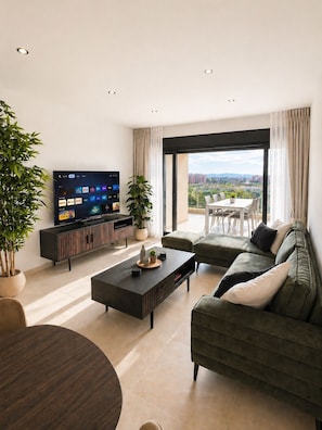 Ein modernes Wohnzimmer mit Flachbildfernseher, Couchtisch, Sofa und Essbereich.