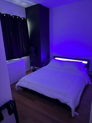 Ein Schlafzimmer mit einem Bett, einem Schminktisch, einem Nachttisch und einer Topfpflanze.