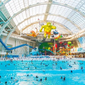 Ein großer Indoor-Wasserpark mit Schwimmbecken, Wasserrutschen und verschiedenen Wasserspielen.