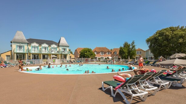 A swimming pool with lounge chairs and a building with a distinctive architectural style. - Bourgenay Flat Near Coastal Slopes (Talmont-Saint-Hilaire)
