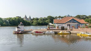 A lakeside building with a red roof, a small tower, and boats docked in the water. - Bourgenay Flat Near Coastal Slopes (Talmont-Saint-Hilaire)