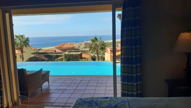 Une chambre avec un lit, une vue sur la piscine et un balcon.