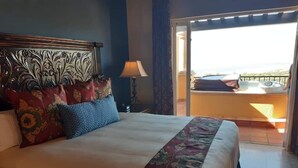 Une chambre d’hôtel avec un grand lit, une table de chevet, une lampe et une vue sur le balcon extérieur.