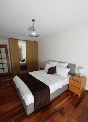Une chambre à coucher comprenant un lit, une table de chevet, une lampe, une armoire et un luminaire au plafond.