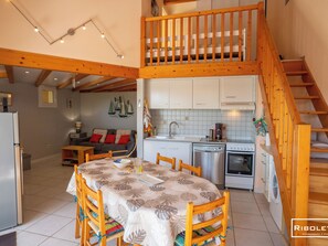 Ein zweistöckiges Haus mit Essbereich, Küche und Treppe.