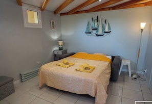 Ein Schlafzimmer mit Bett, Nachttisch, Lampe, Fenster und Wandbild.