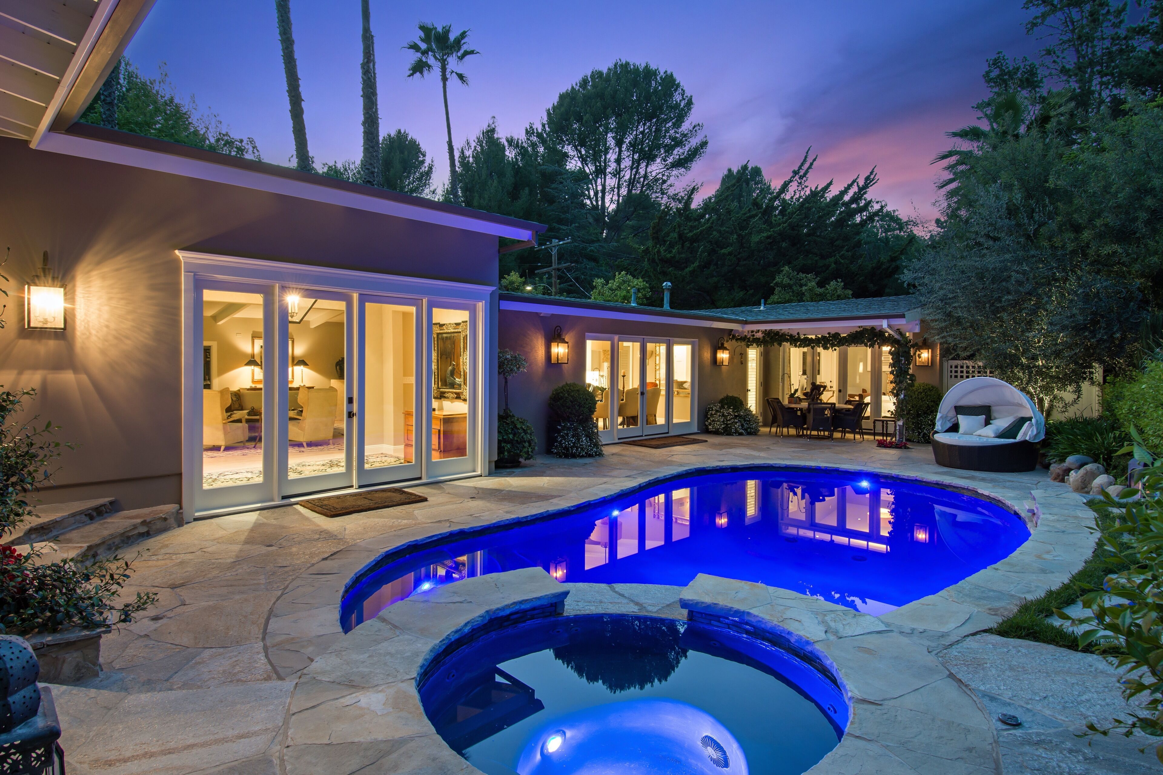 Una casa moderna con piscina, puertas de vidrio e iluminación exterior.