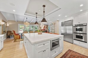A modern kitchen with white cabinetry, stainless steel appliances, and pendant lighting. - Beverly Hills Luxury Private Suite.by Top Interior Designer. 5 Star reviews (Beverly Hills)