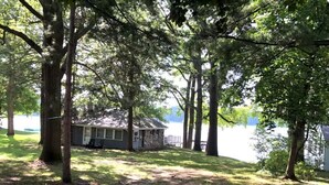 Una cabana vora un llac, envoltada d'arbres.