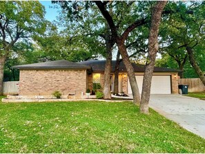 A residential house with a brick exterior, a garage, and a front yard with grass and trees. - DFW Executive Globe Life, ATT Stadium, Six Flags FIFA World Cup Home Arlington (Arlington)
