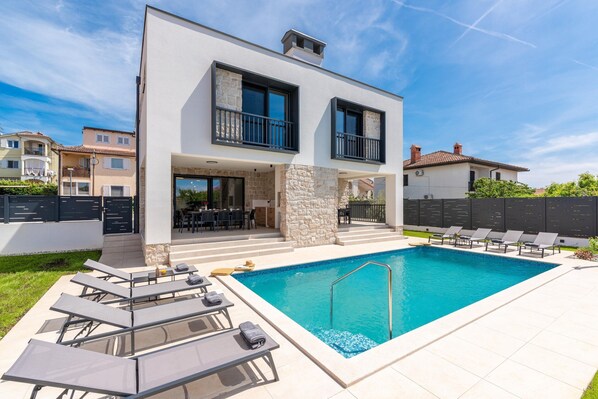 A modern two-story house with a swimming pool, outdoor seating, and a stone facade. - 6-person Home With 3 En-suites (Novigrad)