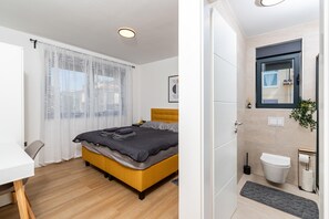 A bedroom with a bed, a desk, and a bathroom with a toilet and sink. - 6-person Home With 3 En-suites (Novigrad)