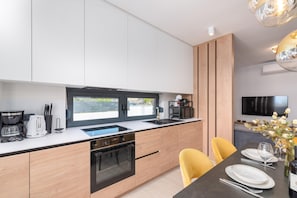 A modern kitchen with a large window, built-in appliances, and a dining area with yellow chairs. - 6-person Home With 3 En-suites (Novigrad)