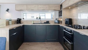 Una cocina moderna con armarios oscuros, una ventana, horno empotrado y una encimera con cafetera.