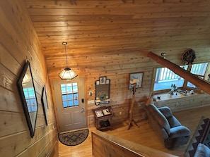 A wooden cabin interior with a door, a ceiling light, a sofa, and a window. - Beautiful log cabin minutes away from Castle Rock lake & Buckhorn St. park (New Lisbon)