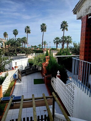 A residential area with a tiled patio, a wooden staircase, and a view of palm trees and a body of water. - PEPA'S PARADISE (BEACH) (Benicassim)
