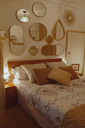 Une chambre à coucher avec un lit, une table de chevet, une commode et un miroir au mur.
