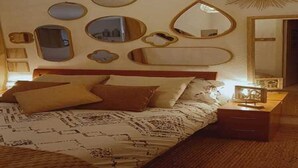 Ein Schlafzimmer mit einem Bett, einem Nachttisch und mehreren Wandspiegeln.