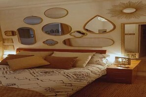Une chambre à coucher avec un lit, une table de chevet et plusieurs miroirs fixés au mur.