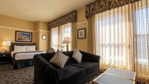 Une chambre d’hôtel avec un lit, un canapé, une table et des rideaux.